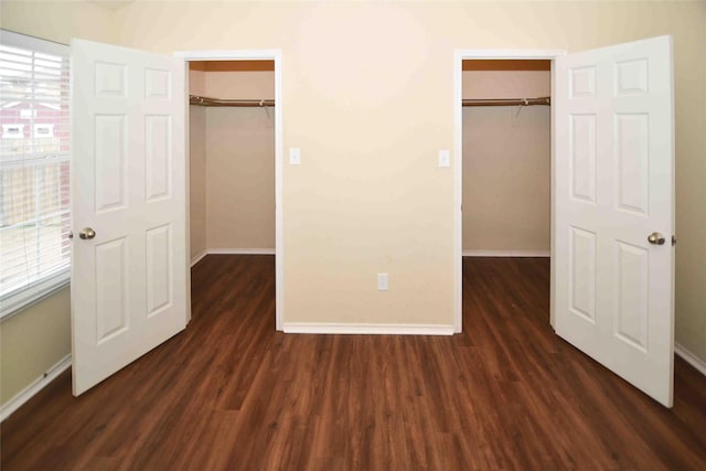 unfurnished bedroom featuring a walk in closet, dark hardwood / wood-style floors, and a closet