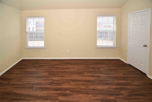 spare room with vaulted ceiling, a healthy amount of sunlight, and dark wood-type flooring