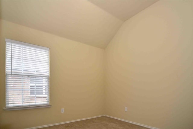 carpeted spare room with lofted ceiling