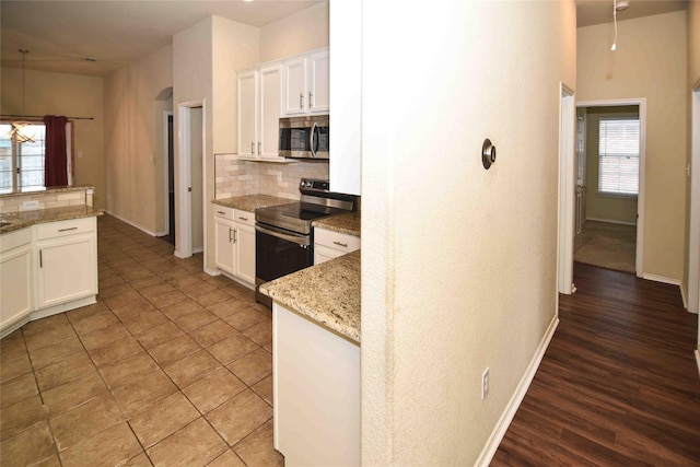 kitchen with light stone countertops, stainless steel appliances, and white cabinets