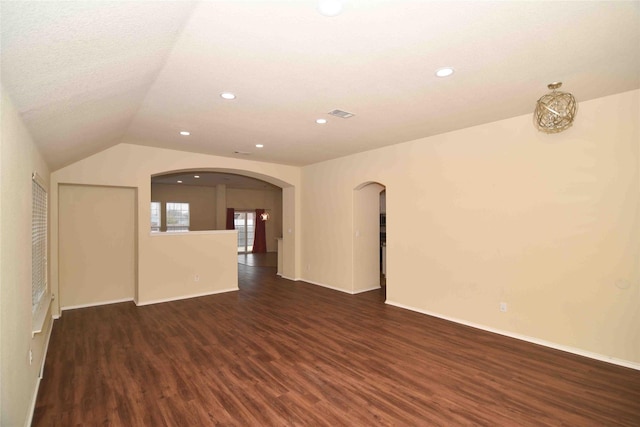 empty room with lofted ceiling, dark hardwood / wood-style floors, and a textured ceiling