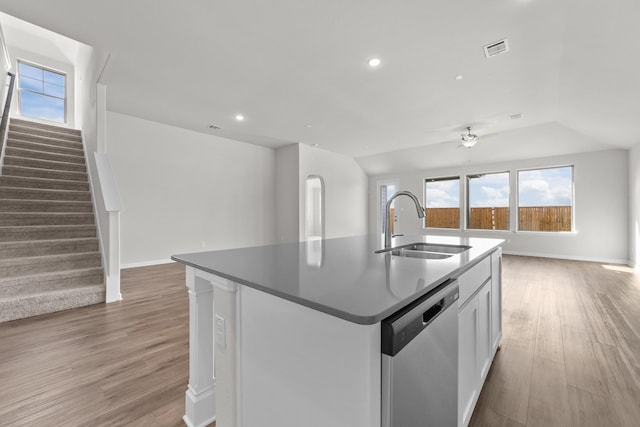 kitchen featuring sink, white cabinets, hardwood / wood-style flooring, stainless steel dishwasher, and a center island with sink