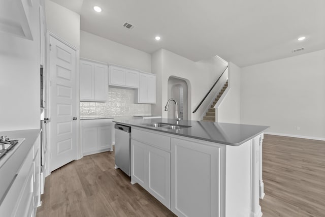 kitchen with sink, white cabinetry, light hardwood / wood-style floors, a center island with sink, and stainless steel dishwasher