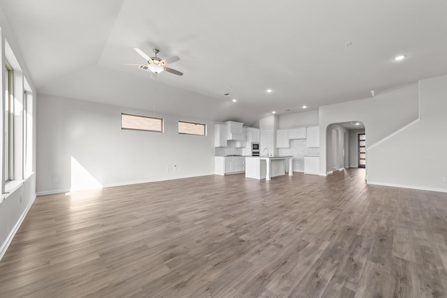 unfurnished living room featuring sink, dark wood-type flooring, ceiling fan, and vaulted ceiling