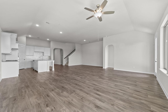 unfurnished living room with ceiling fan, lofted ceiling, sink, and light hardwood / wood-style flooring