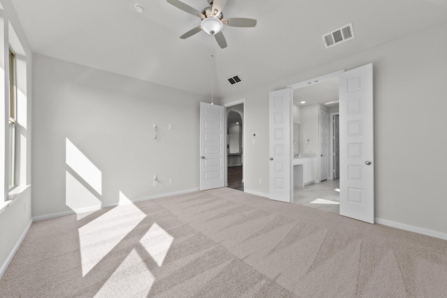 unfurnished bedroom featuring light carpet, ceiling fan, and ensuite bathroom