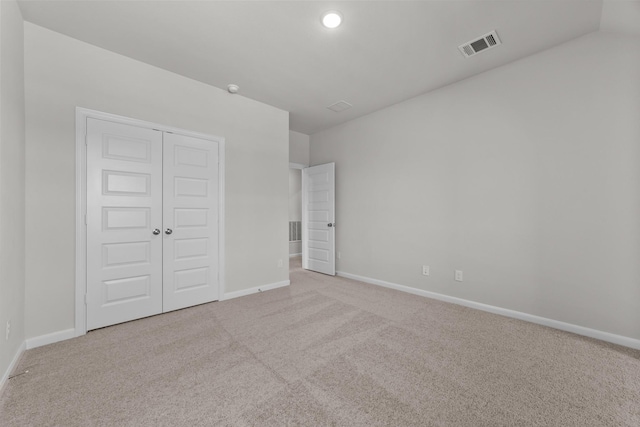 unfurnished bedroom with light colored carpet and a closet