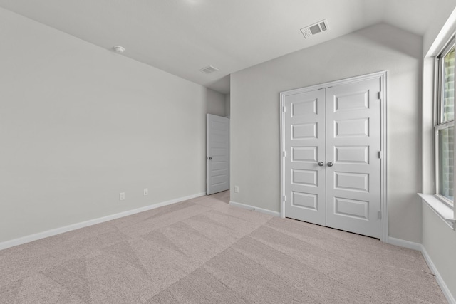 unfurnished bedroom with light carpet, vaulted ceiling, and a closet