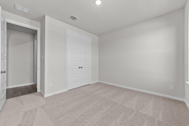 unfurnished bedroom featuring light colored carpet and a closet