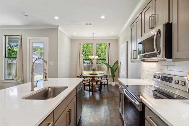 kitchen featuring sink, appliances with stainless steel finishes, ornamental molding, light stone countertops, and decorative light fixtures