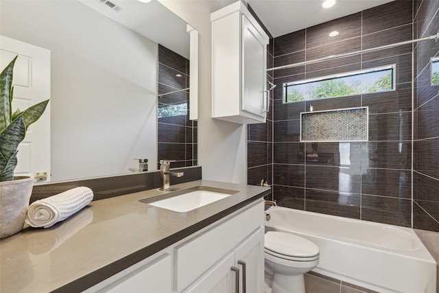 full bathroom featuring vanity, tiled shower / bath combo, and toilet