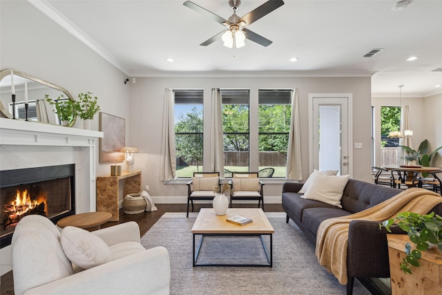 living room featuring ceiling fan, ornamental molding, a premium fireplace, and wood-type flooring