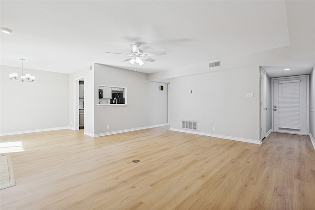 unfurnished living room with ceiling fan with notable chandelier and light wood-type flooring