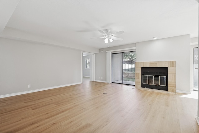 unfurnished living room with a tiled fireplace, ceiling fan, and light hardwood / wood-style flooring