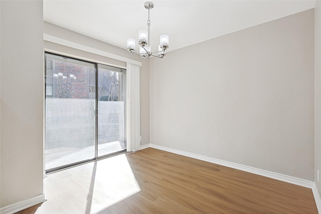 empty room featuring an inviting chandelier and hardwood / wood-style floors