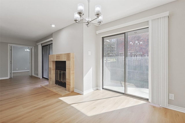 unfurnished living room with a fireplace, a notable chandelier, and wood-type flooring