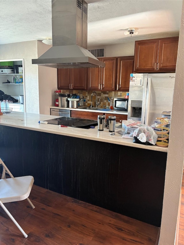 kitchen with a textured ceiling, appliances with stainless steel finishes, kitchen peninsula, and island exhaust hood