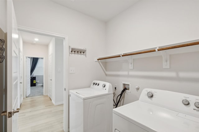 laundry room featuring washing machine and clothes dryer and light hardwood / wood-style flooring