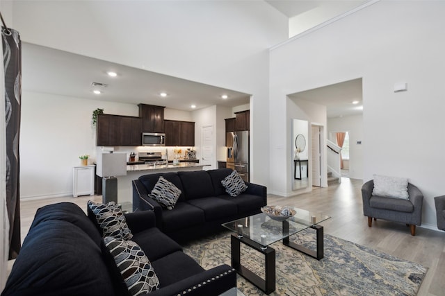 living room featuring a towering ceiling and light hardwood / wood-style flooring