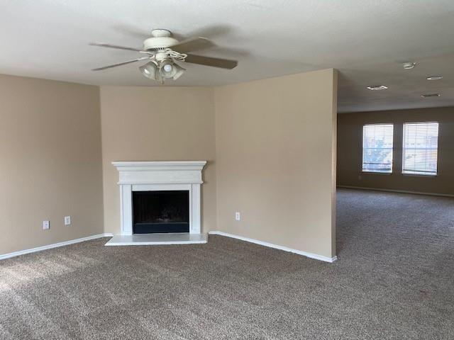 unfurnished living room with ceiling fan and dark colored carpet