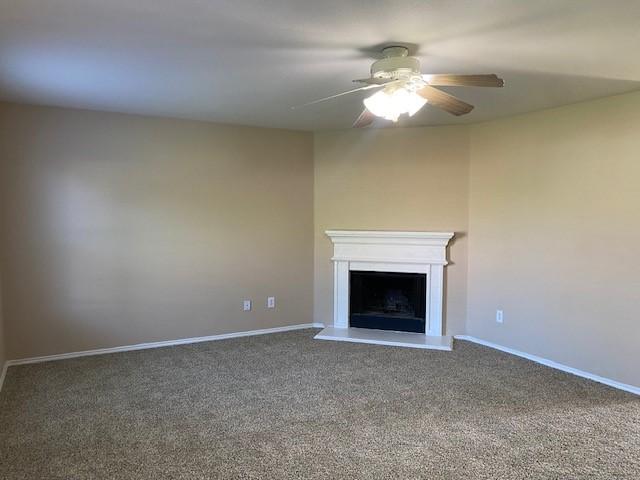 14029 Coyote Trl, Fort Worth, TX 76052 - unfurnished living room with a ceiling fan, baseboards, a fireplace with raised hearth, and carpet