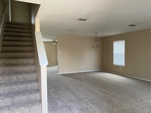 carpeted spare room featuring a notable chandelier