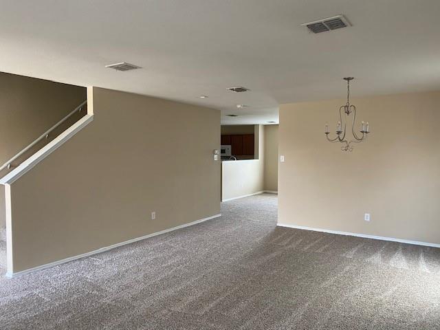 carpeted spare room featuring a chandelier