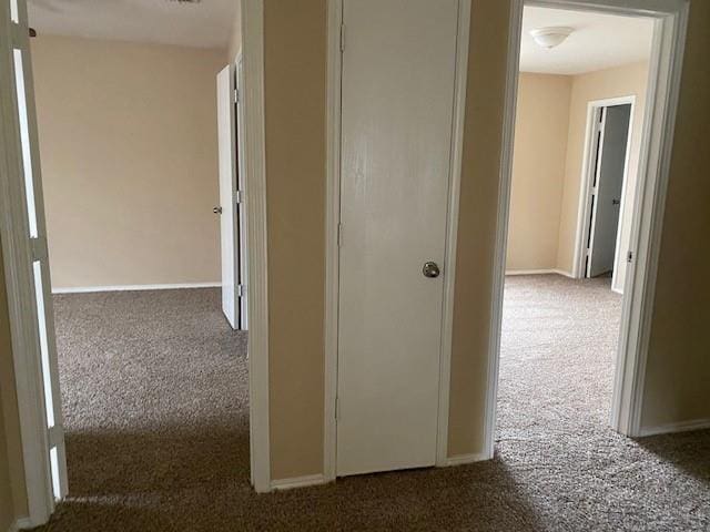 hallway featuring dark colored carpet