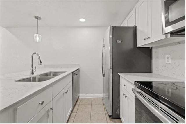 kitchen featuring sink, white cabinetry, stainless steel appliances, light tile patterned flooring, and decorative light fixtures