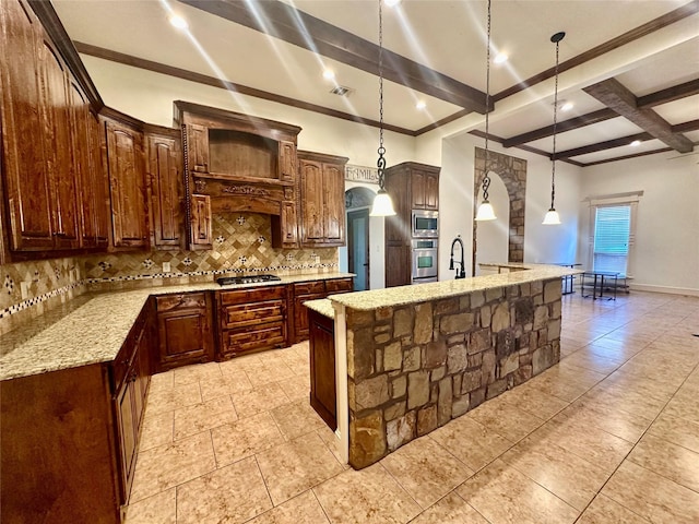 kitchen with hanging light fixtures, a center island with sink, decorative backsplash, and stainless steel appliances