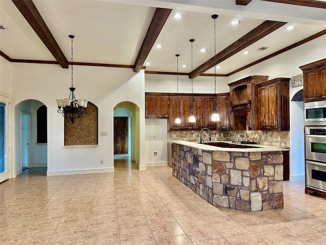 kitchen with a spacious island, backsplash, dark brown cabinetry, and decorative light fixtures