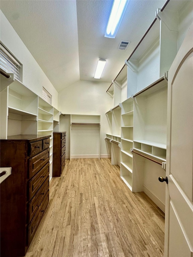 spacious closet with vaulted ceiling and light hardwood / wood-style floors