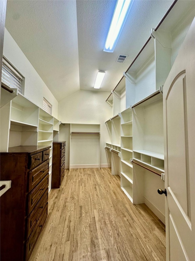 walk in closet featuring lofted ceiling and light hardwood / wood-style floors