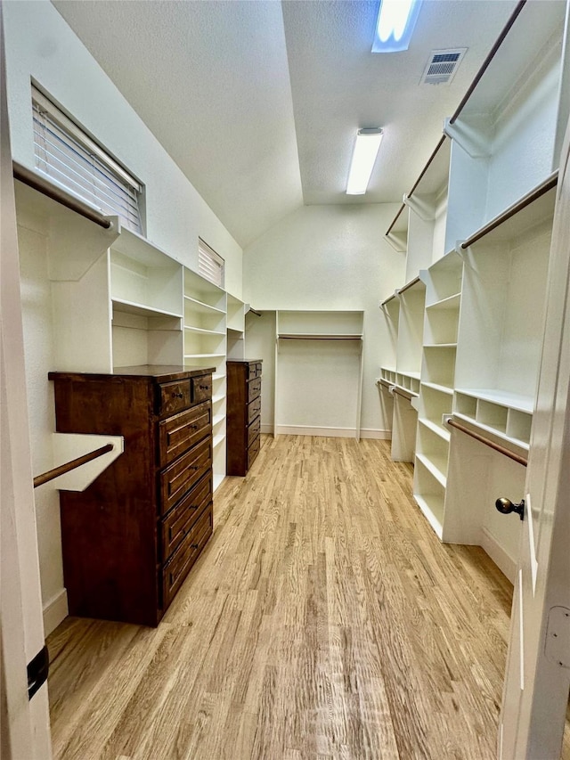 spacious closet featuring lofted ceiling and light hardwood / wood-style flooring