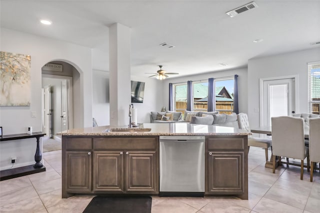 kitchen featuring stainless steel dishwasher, a kitchen island with sink, sink, and dark brown cabinets