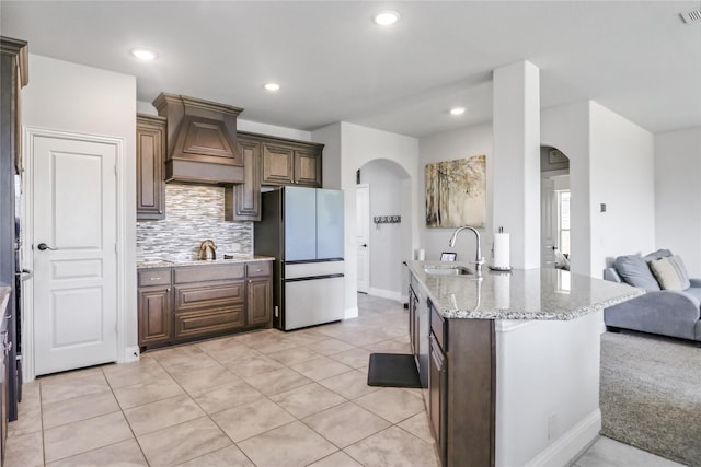 kitchen with premium range hood, tasteful backsplash, sink, fridge, and black electric stovetop