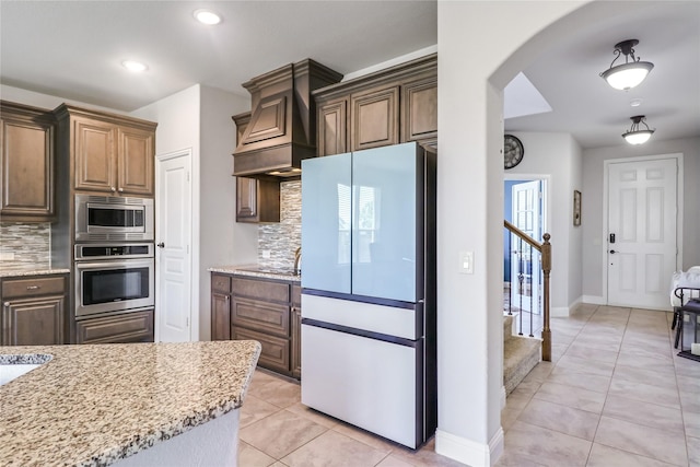 kitchen featuring stainless steel appliances, tasteful backsplash, light tile patterned floors, and light stone counters