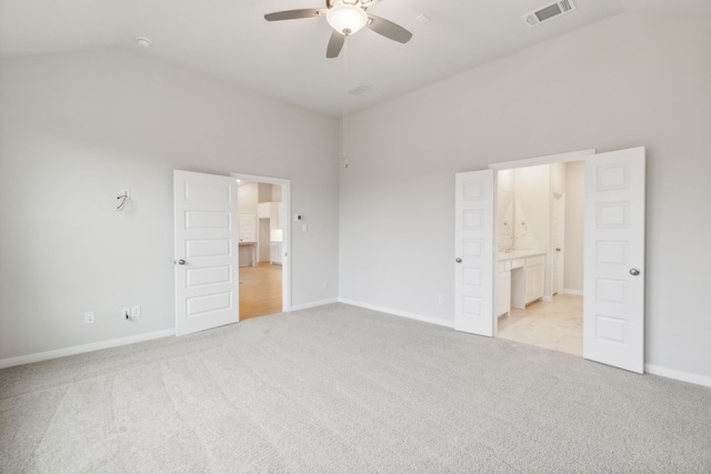 unfurnished bedroom with vaulted ceiling, connected bathroom, light carpet, and ceiling fan