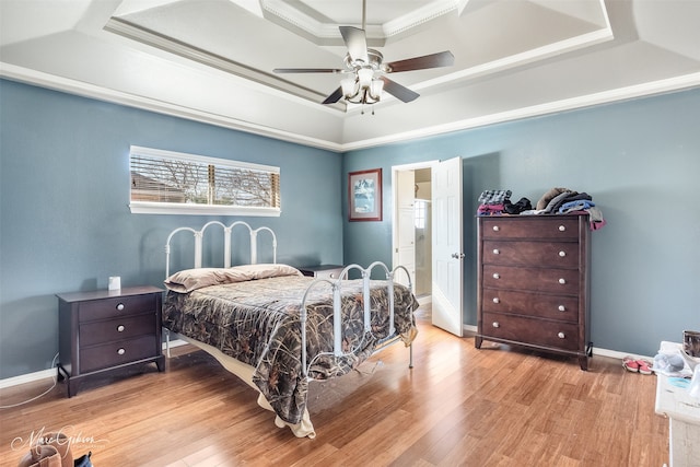 bedroom featuring ornamental molding, a tray ceiling, ceiling fan, and light hardwood / wood-style flooring