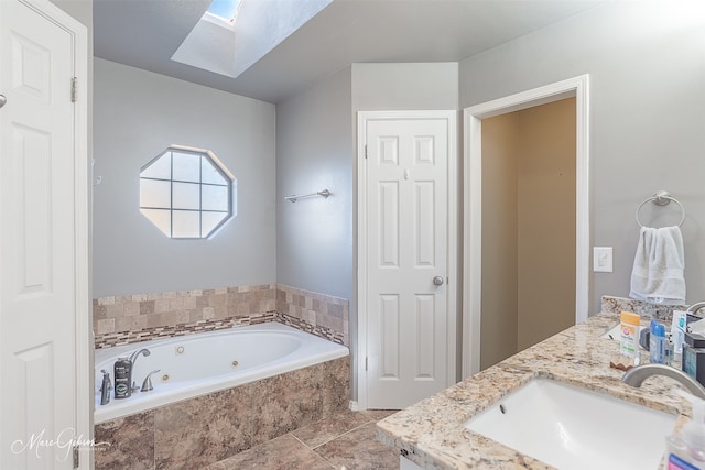 bathroom with vanity, tiled bath, and a skylight