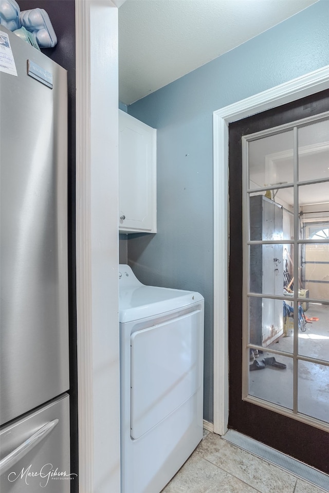 clothes washing area featuring light tile patterned flooring, cabinets, and washer / clothes dryer