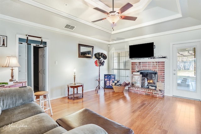 living room featuring crown molding, a tray ceiling, a wealth of natural light, and hardwood / wood-style flooring