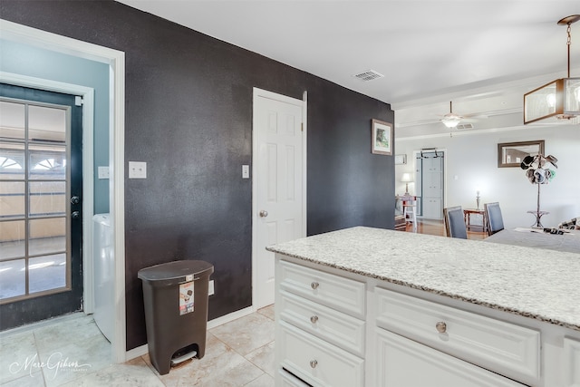 kitchen with white cabinetry, light stone counters, ceiling fan, and decorative light fixtures