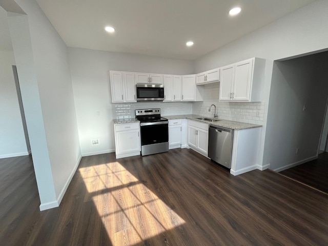 kitchen featuring appliances with stainless steel finishes, white cabinetry, sink, dark hardwood / wood-style flooring, and decorative backsplash