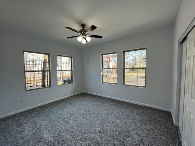 unfurnished bedroom featuring ceiling fan, dark carpet, and a closet