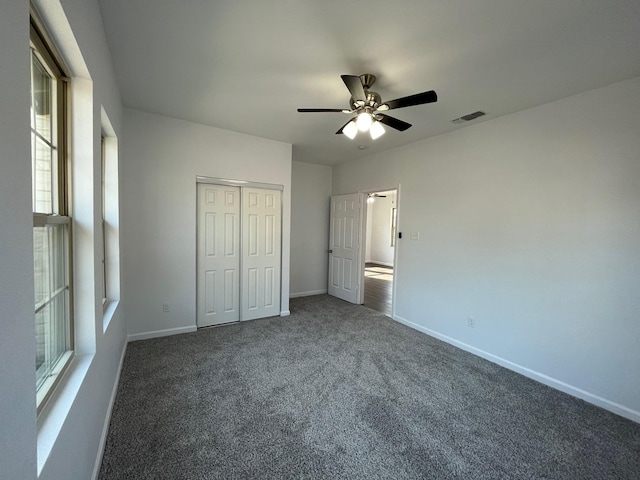 unfurnished bedroom featuring ceiling fan, dark carpet, and a closet