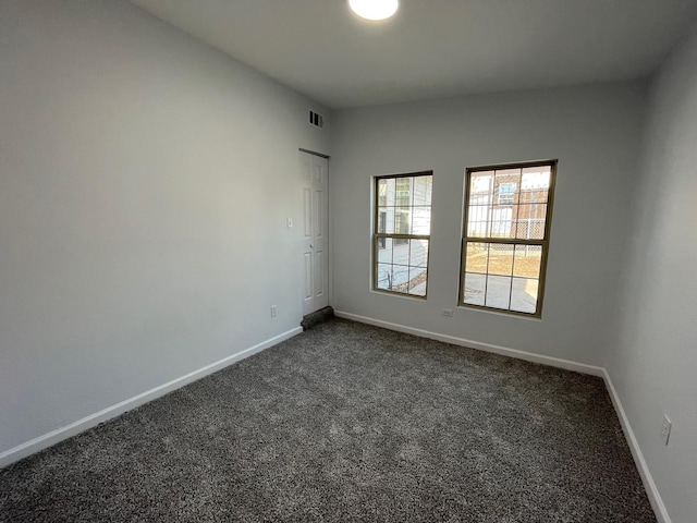 spare room with dark carpet