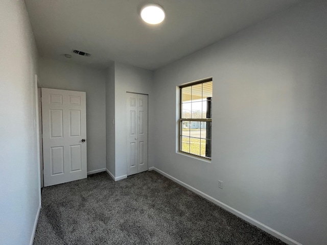 unfurnished bedroom featuring a closet and dark colored carpet