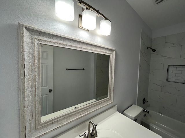 full bathroom featuring tiled shower / bath, vanity, and toilet