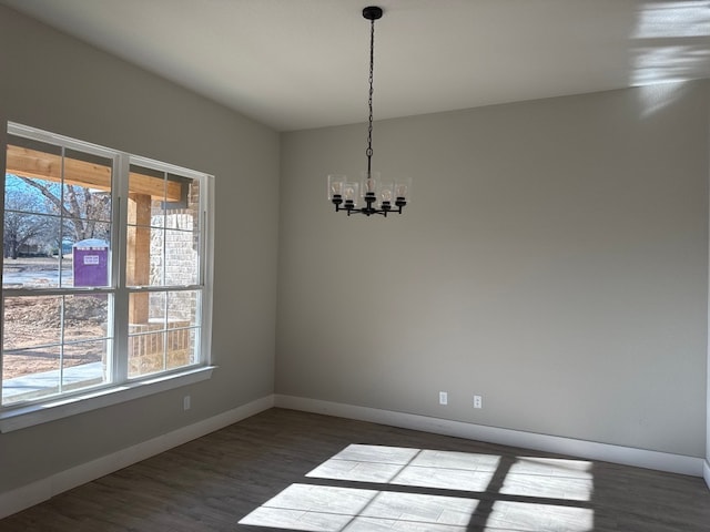 spare room with hardwood / wood-style floors and a notable chandelier